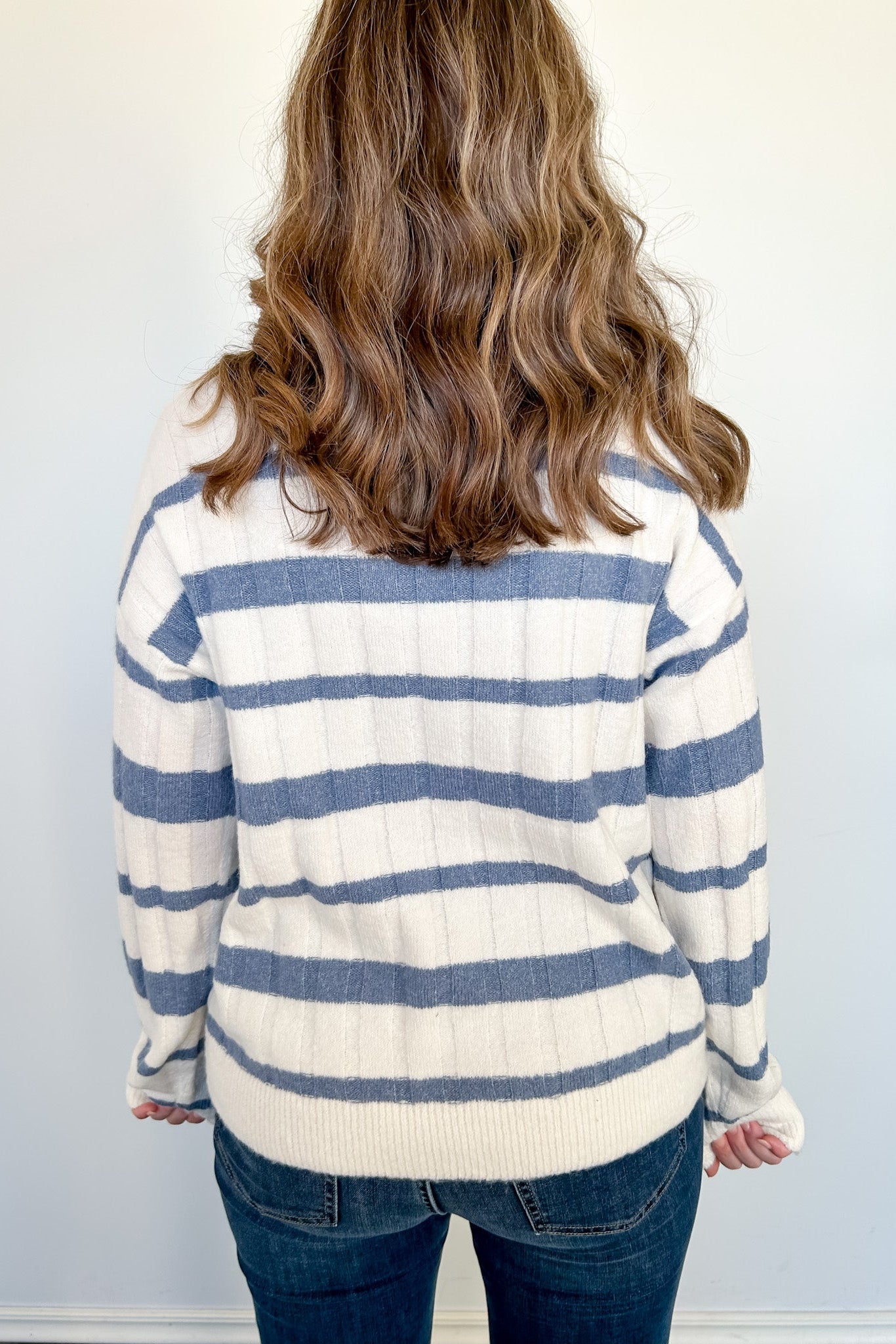 Person wearing a striped sweater with blue and white horizontal stripes against a plain background