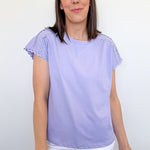 Woman wearing a light purple top with ruffled sleeves against a white background