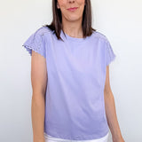 Woman wearing a light purple top with ruffled sleeves against a white background