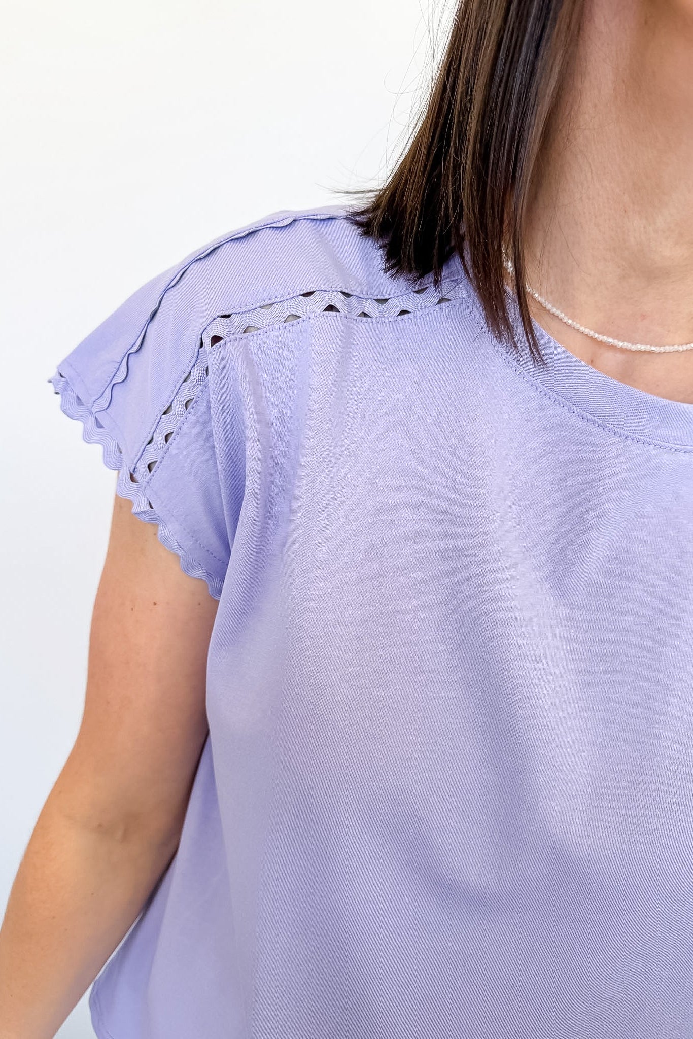 Light purple top with lace details on sleeves against a white background
