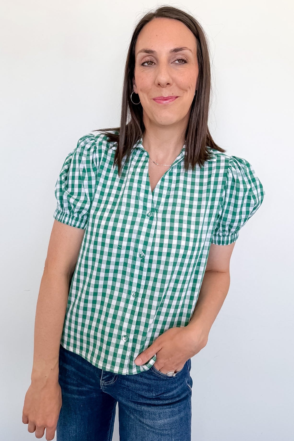 Woman wearing a green and white checkered shirt against a white background