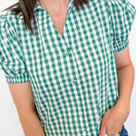 Person wearing a green and white checkered shirt with blue jeans against a plain background