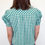 Person wearing a green and white checkered blouse against a white background