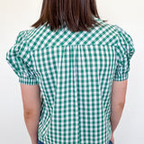 Person wearing a green and white checkered blouse against a white background