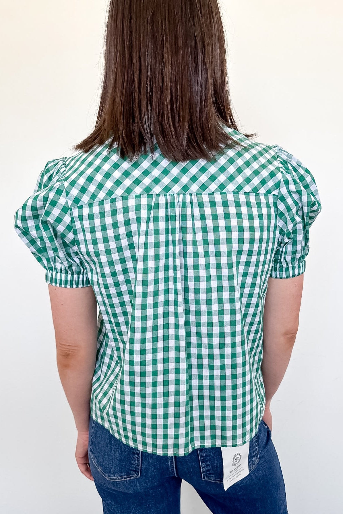Person wearing a green and white checkered blouse against a white background