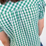Person wearing a green and white checkered shirt against a white background