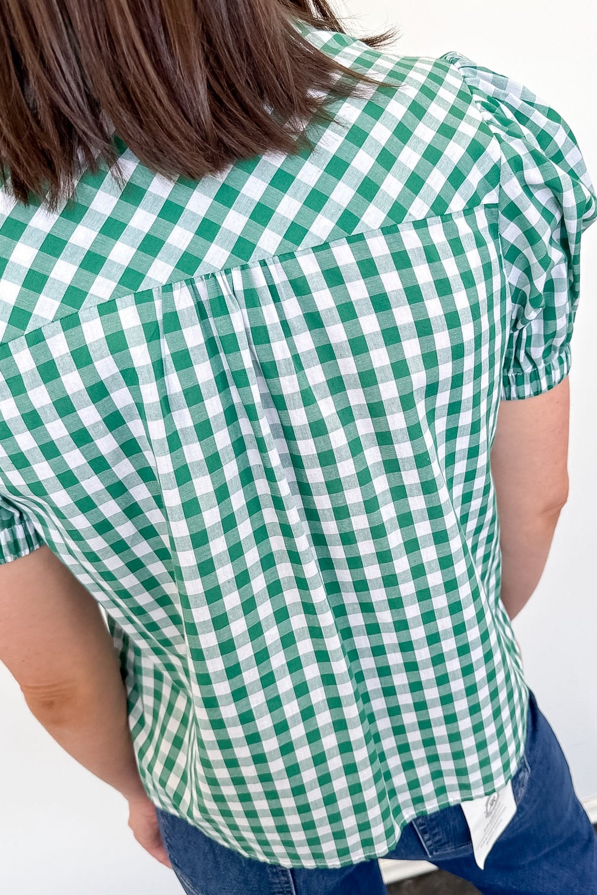 Person wearing a green and white checkered shirt against a white background