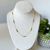 Necklace on a white bust with a plant in the background