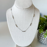 Necklace on a white bust with a plant in the background