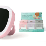 Pink handheld mirror with black surface next to a box of skincare products on a white background