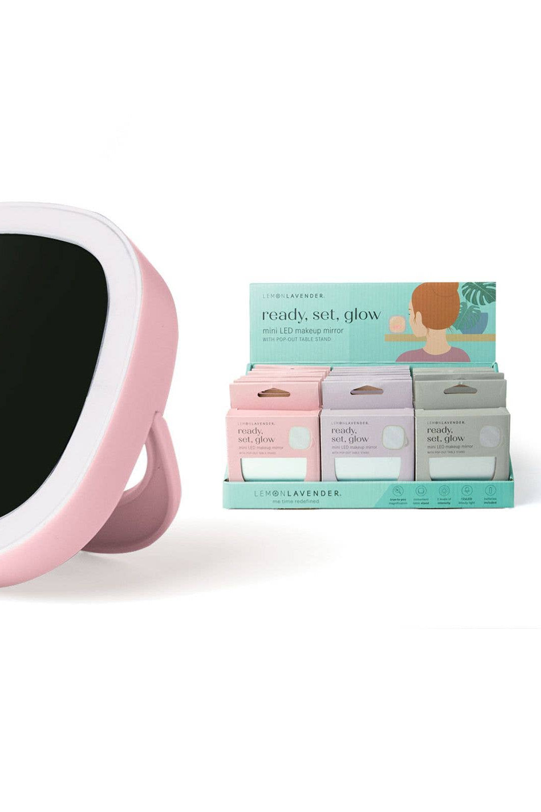 Pink handheld mirror with black surface next to a box of skincare products on a white background