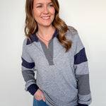 Woman wearing a gray and navy striped sweater with blue pants against a white background
