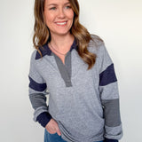 Woman wearing a gray and navy striped sweater with blue pants against a white background
