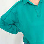Person wearing a teal long-sleeve shirt against a white background