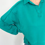 Person wearing a teal long-sleeve shirt against a white background