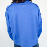 Person wearing a blue sweatshirt against a white wall