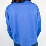 Person wearing a blue sweatshirt against a white wall