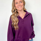 Woman wearing a purple hoodie and blue jeans against a white background