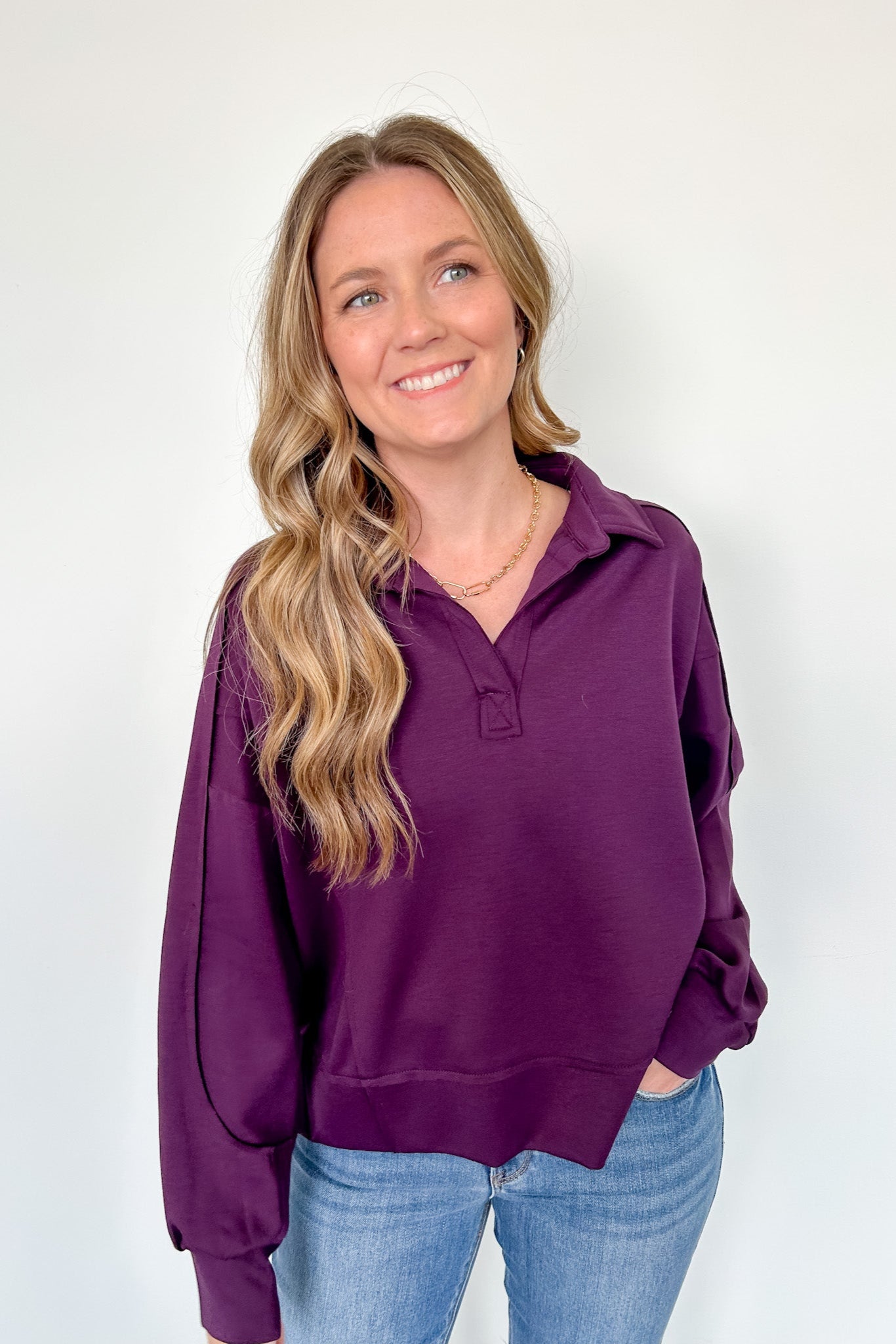 Woman wearing a purple hoodie and blue jeans against a white background