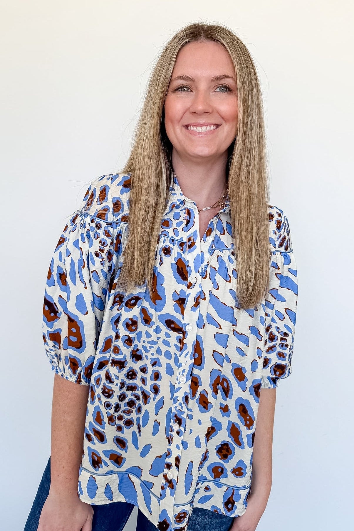 Woman wearing a patterned blouse against a plain background