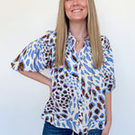 Woman wearing a patterned blouse and jeans against a white background