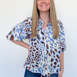 Woman wearing a patterned blouse and jeans against a white background