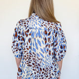Person wearing a blue and brown patterned blouse against a white background