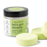 Jar of 'let's get steamy' shower steamers with three green tablets on a white background