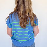 Person wearing a blue and green striped shirt against a white background