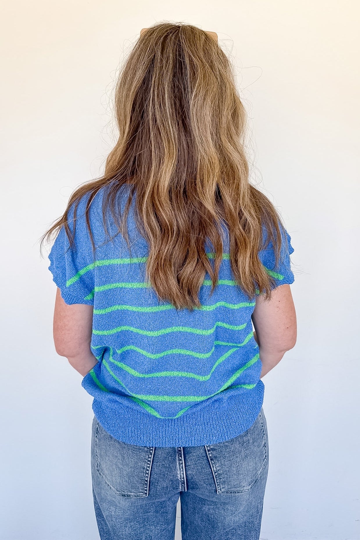 Person wearing a blue and green striped shirt against a white background
