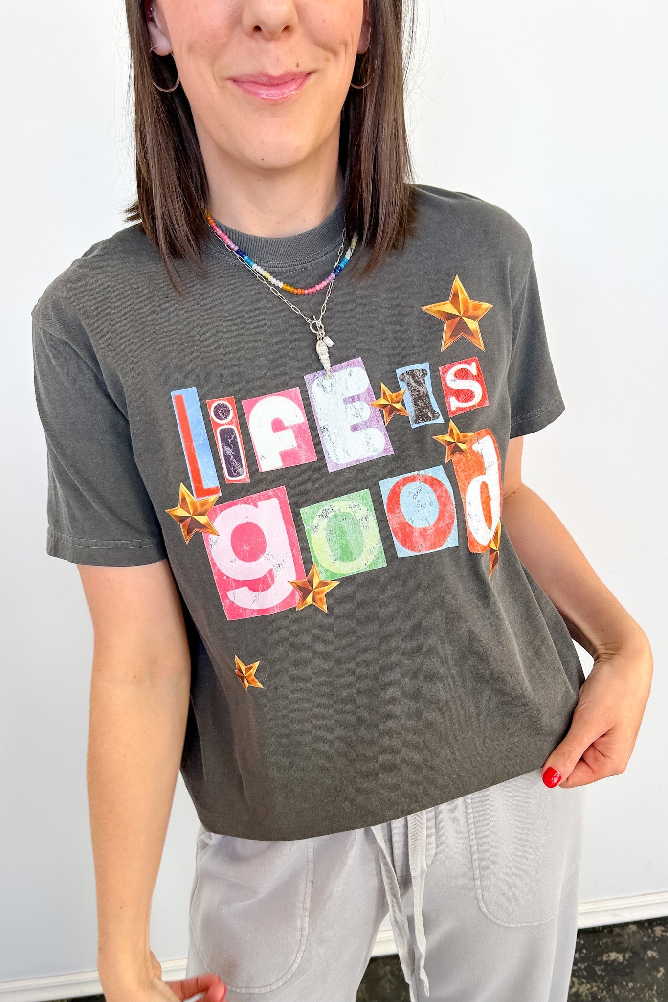 Person wearing a gray t-shirt with colorful text design on a white background