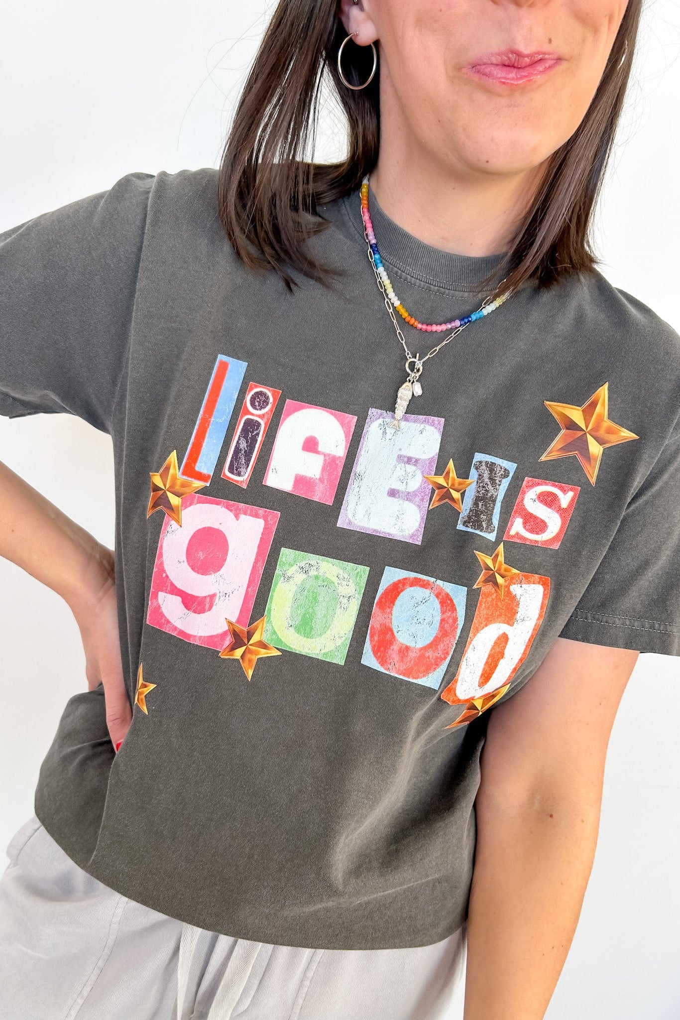 Person wearing a gray t-shirt with colorful text design on a white background