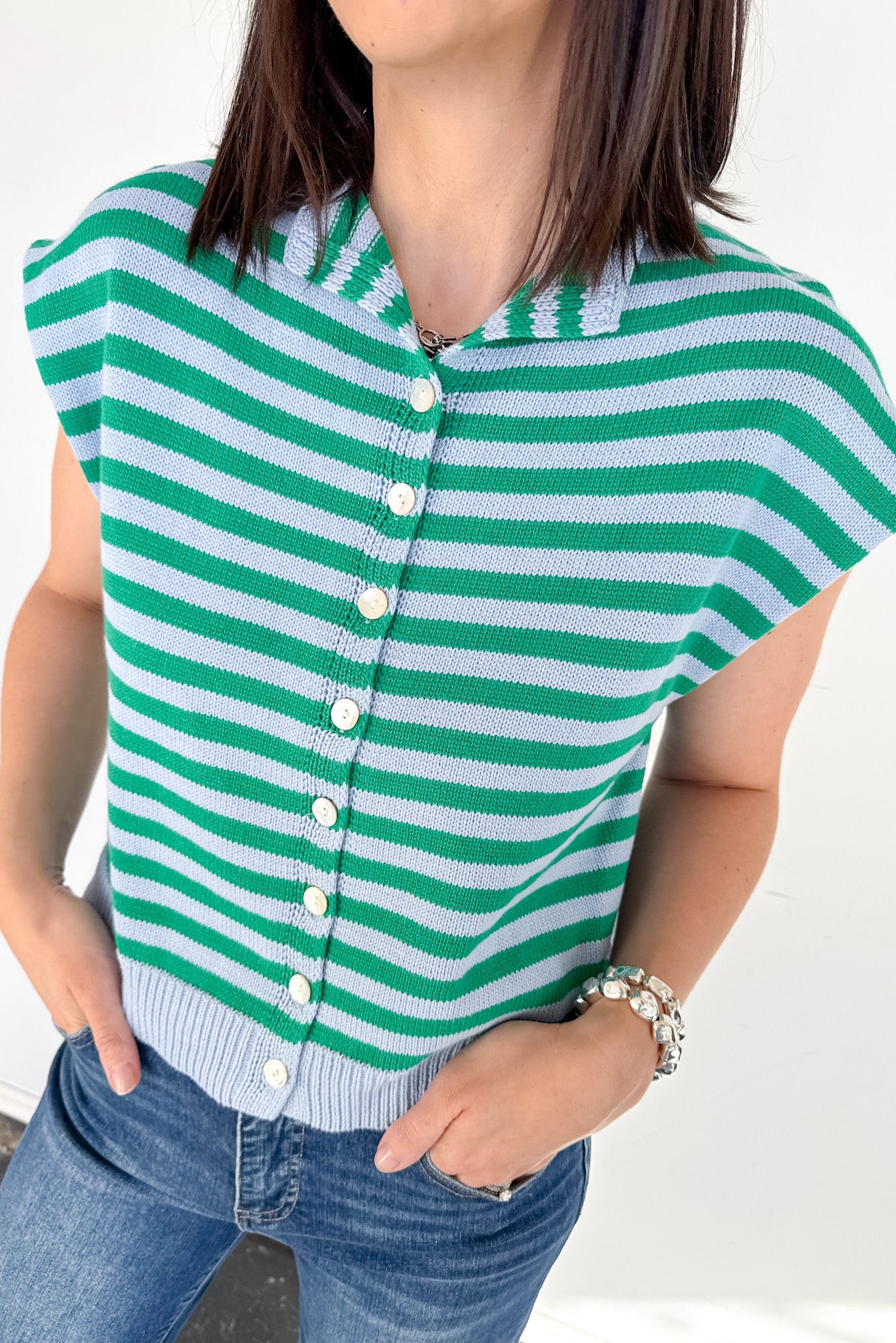 Person wearing a green and white striped cardigan with a plain background