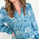 Woman wearing a blue patterned blouse with a white background