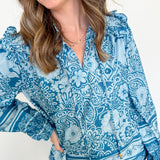 Woman wearing a blue patterned blouse with a white background
