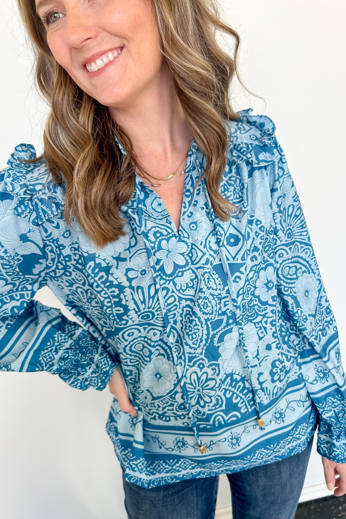 Woman wearing a blue patterned blouse with a white background