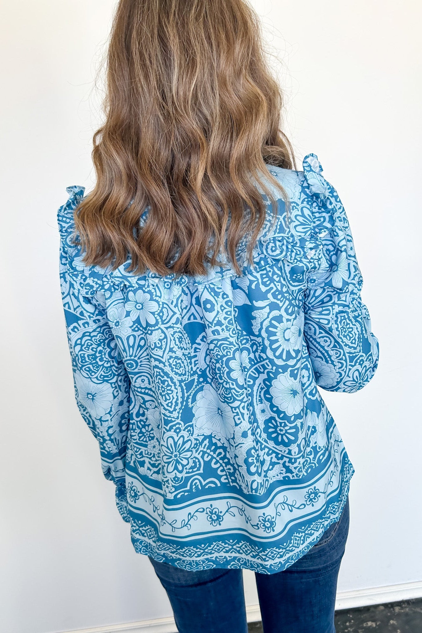 Person wearing a blue patterned blouse against a white background