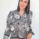 Woman wearing a black and white patterned blouse against a plain background