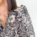 Black and white patterned blouse worn by a person on a plain background