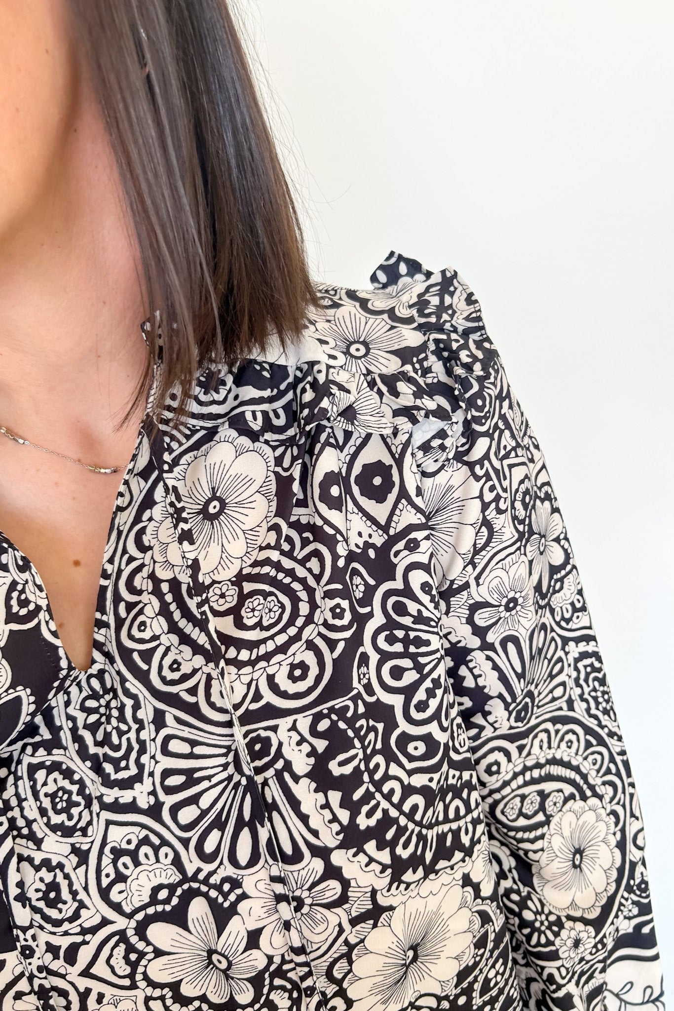 Black and white patterned blouse worn by a person on a plain background