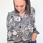 Woman wearing a black and white patterned blouse with blue jeans on a white background