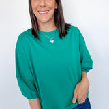 Woman wearing a green top and blue jeans against a white background