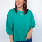 Woman wearing a green top and blue jeans against a white background