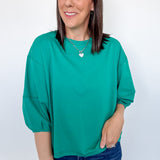 Woman wearing a green top and blue jeans against a white background