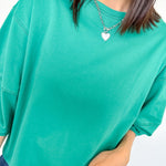 Person wearing a teal oversized t-shirt and blue jeans on a white background