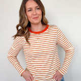 Woman wearing a striped long-sleeve shirt with orange and white stripes against a plain background