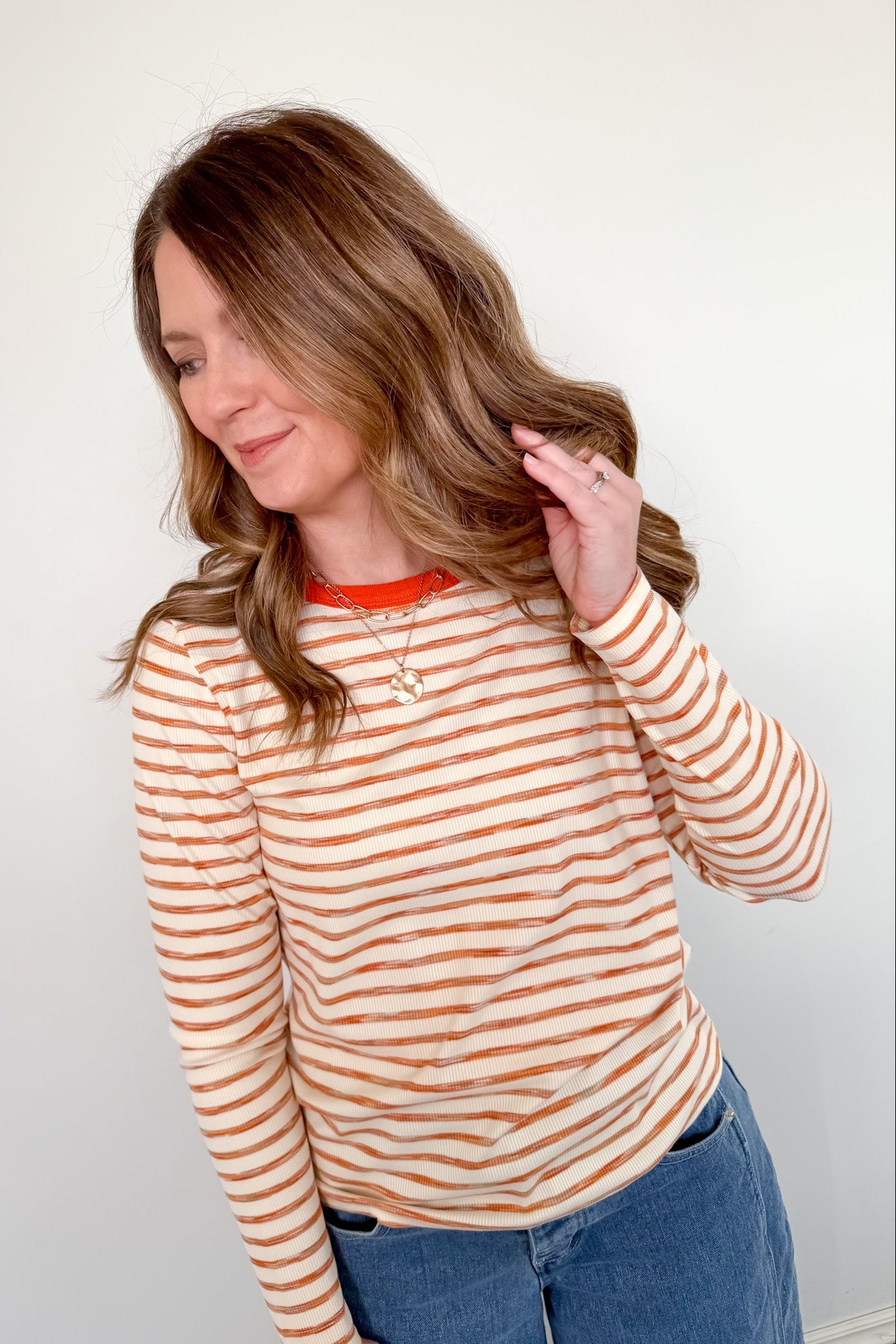 Woman wearing a striped long-sleeve shirt with a plain background