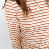 Person wearing a striped long-sleeve shirt with orange and white stripes on a plain background