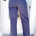 Person wearing navy pants and a striped shirt standing in front of a door.