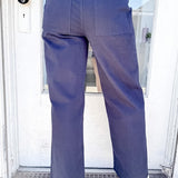 Person wearing navy pants and a striped shirt standing in front of a door.